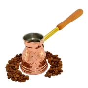 Handmade engraved copper briki with a wooden handle, shown on a white background with coffee beans