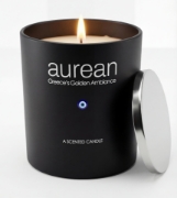 Close-up of Aurean Nox Luxury Candle in a matte black jar with a silver lid and the Greek evil eye emblem, illuminated by a warm flame.