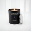 Close-up of Aurean Nox Luxury Candle in a matte black jar with a silver lid and the Greek evil eye emblem, illuminated by a warm flame.