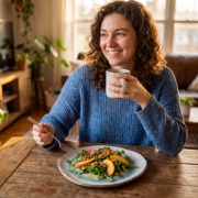 A woman in a kitchen plating fresh hummus onto an Aegean Eye handmade ceramic plate.